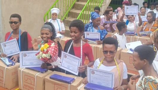 Sewing School graduates celebrating with diplomas and sewing machines